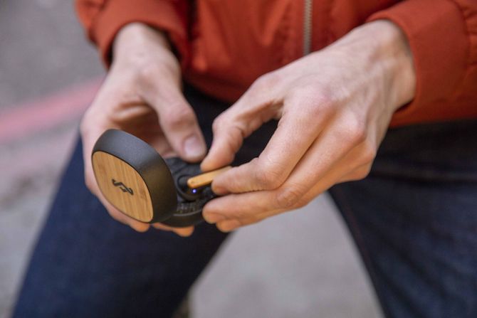 Hands holding the House of Marley Redemption ANC Earbuds